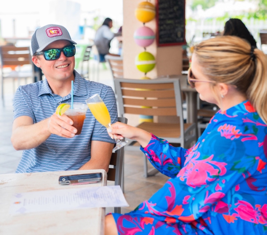 A couple toasting drinks on the open-air waterfront patio at Bayside Grille in Key Largo