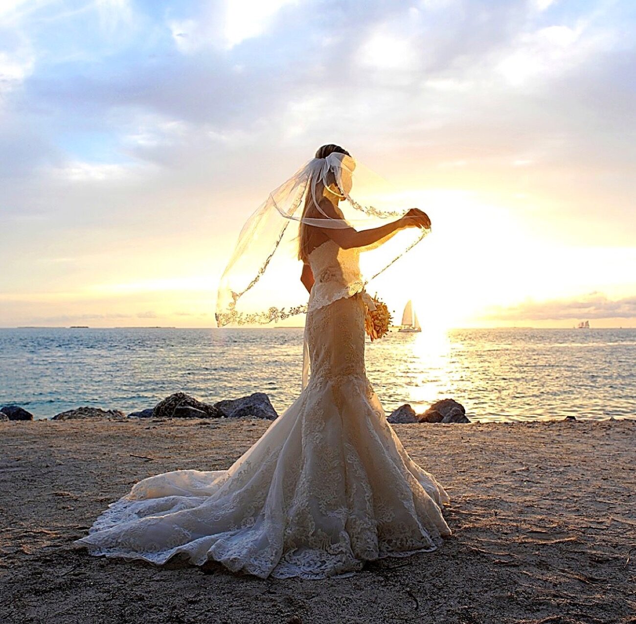 Bride in a lace gown and veil on a Key Largo beach at sunset