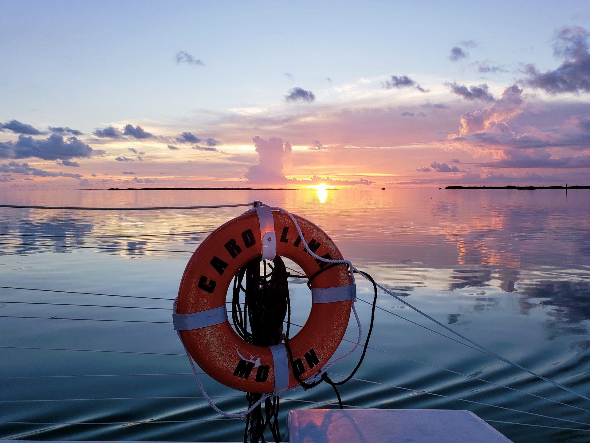 Mirror-calm Florida Bay at dawn from the deck of the Carolina Moon, pastel sky reflected on glassy water