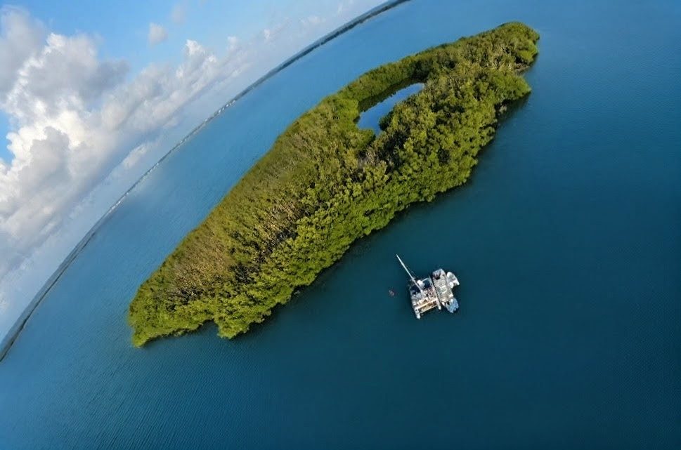 Aerial view of a boat anchored beside an undisturbed mangrove island in the turquoise water of Florida Bay