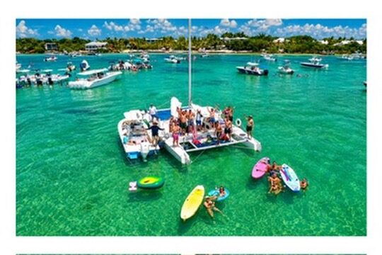 Aerial view of the Carolina Moon catamaran anchored at a Florida Keys sandbar with guests floating in the clear turquoise shallows